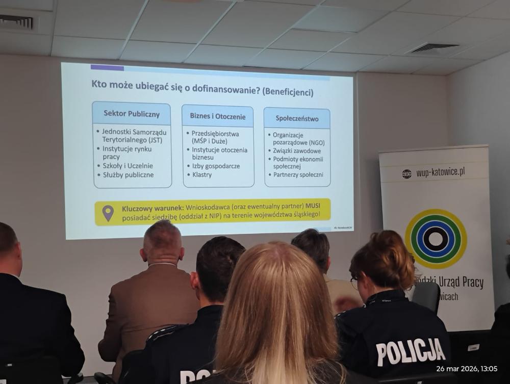 Grupa osób uczestnicząca w spotkaniu informacyjnym, patrząca na wyświetlany slajd dotyczący informacji o tym kto może zostać beneficjentem projektu: sektor publiczny, przedsiębiorstwa i instytucji z otoczenia biznesu oraz organizacje pozarządowe, związki zawodowe, podmioty ekonomii społecznej oraz partnerzy społeczni.