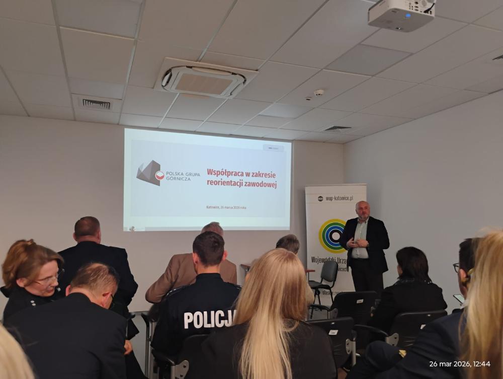Osoby uczestniczące w spotkaniu informacyjnym, patrzące na slajd prezentacji dotyczącym współpracy w zakresie reorientacji zawodowej Polskiej Grupy Górniczej.